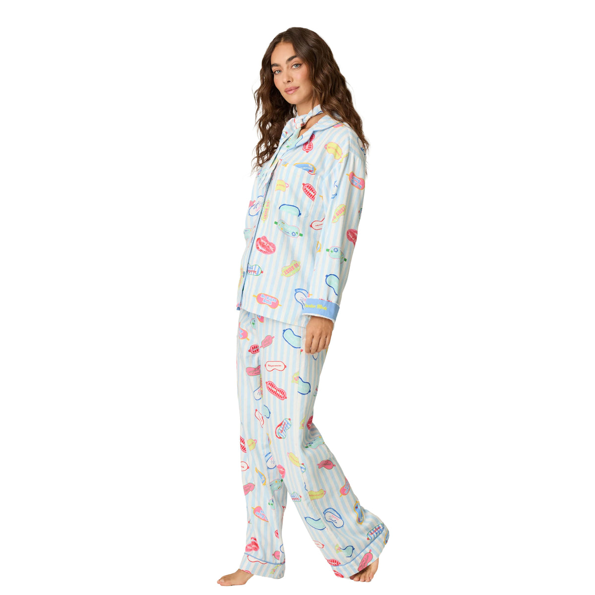 Side view of woman wearing blue and white striped vacation-themed pajamas with colourful playful graphics and blue trim.