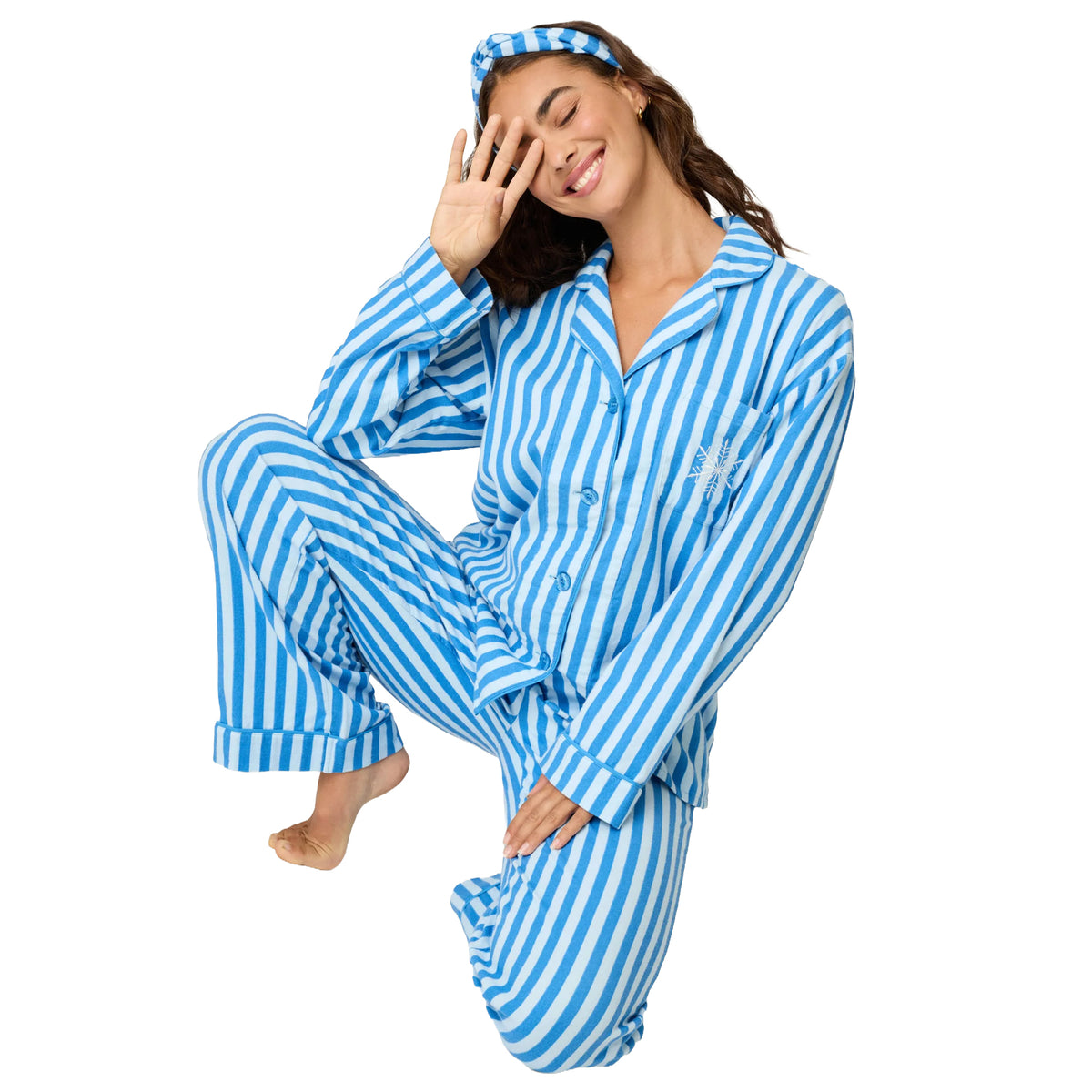 Model posing in blue and white striped flannel pajamas with embroidered snowflake chest pocket, seated pose.