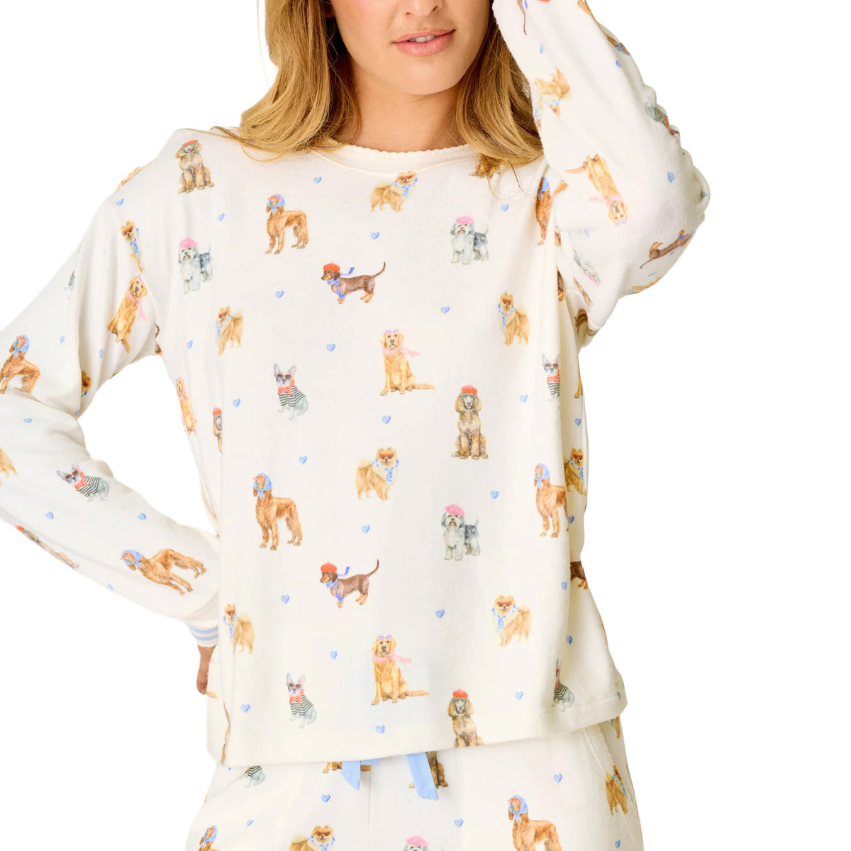Close-up of ivory pajama top featuring colourful French-inspired dog illustrations and small blue hearts.