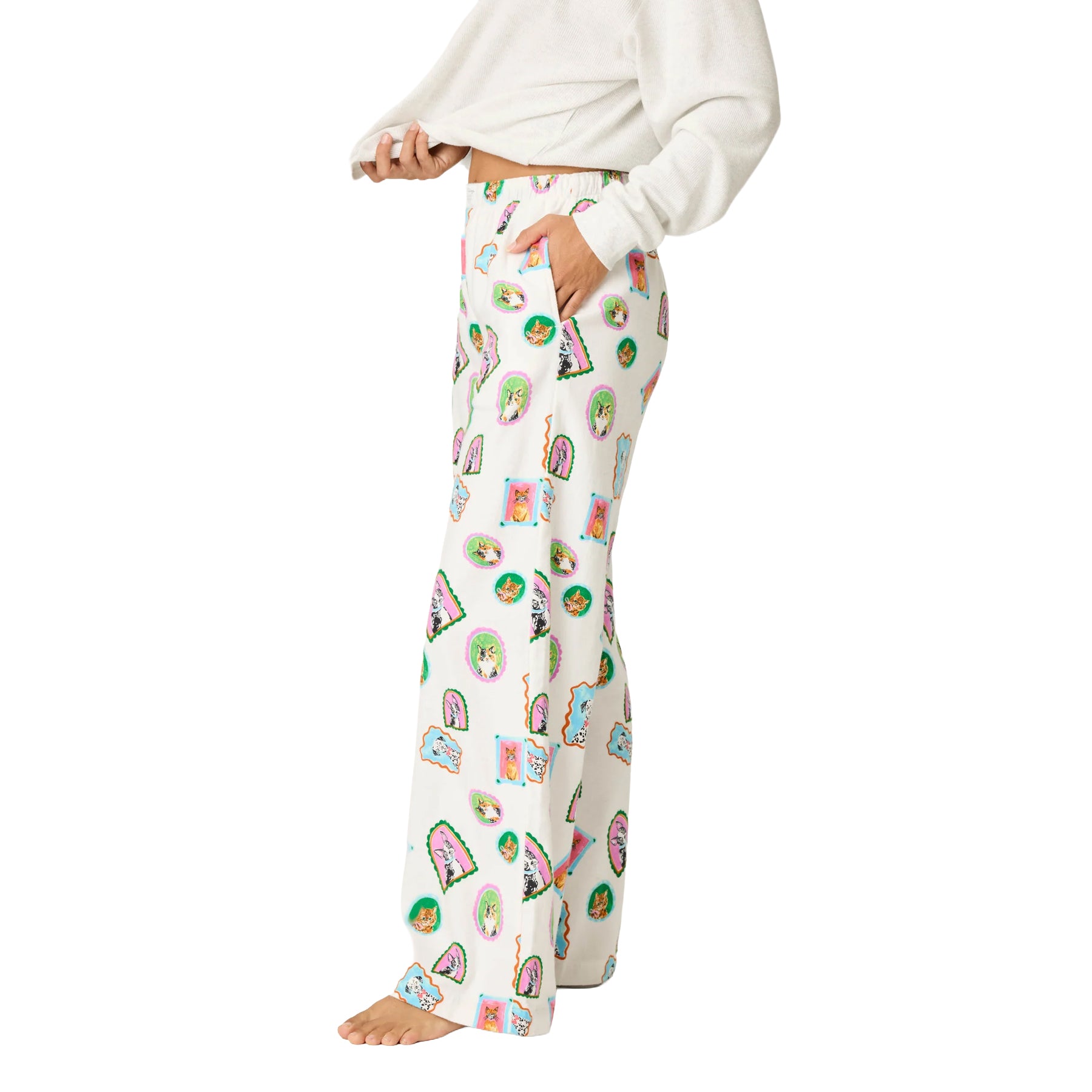 Side view of cream printed pajama pants with colorful dog and cat illustrations, relaxed wide-leg fit and side pocket.