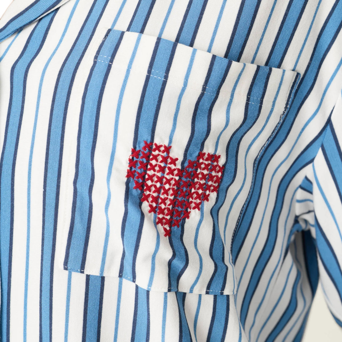 Close-up of the chest pocket on a blue and white striped sleep shirt featuring a red embroidered heart.