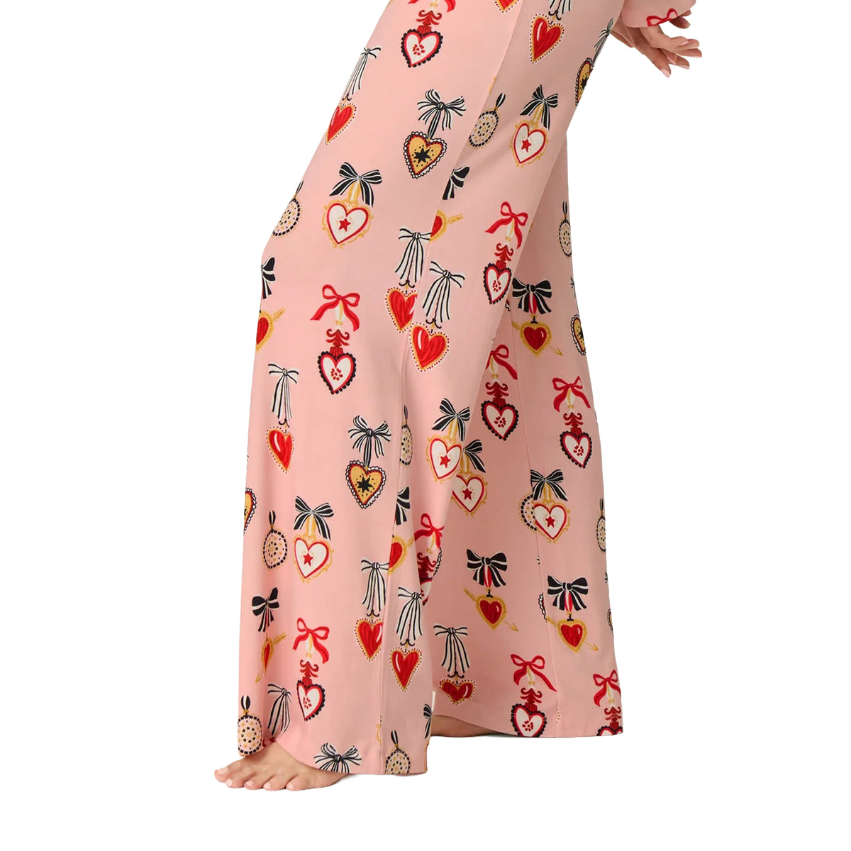 Close-up of PJ Salvage modal pyjama pants showing wide-leg fit and colourful red hearts, black bows and yellow accents on pink fabric.