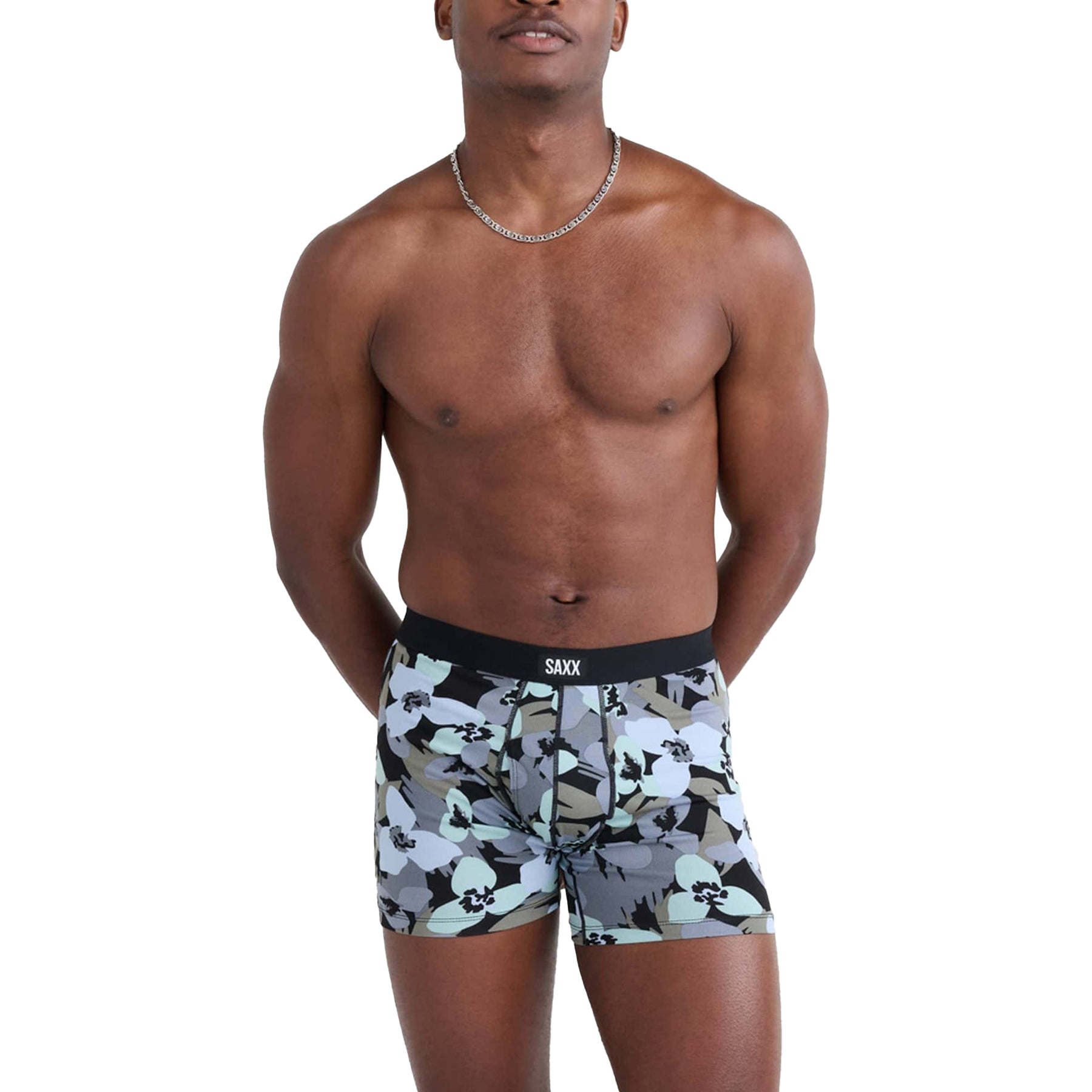 Front view of model in SAXX boxer briefs featuring camo floral print in blue, black, and olive - relaxed fit with logo waistband.