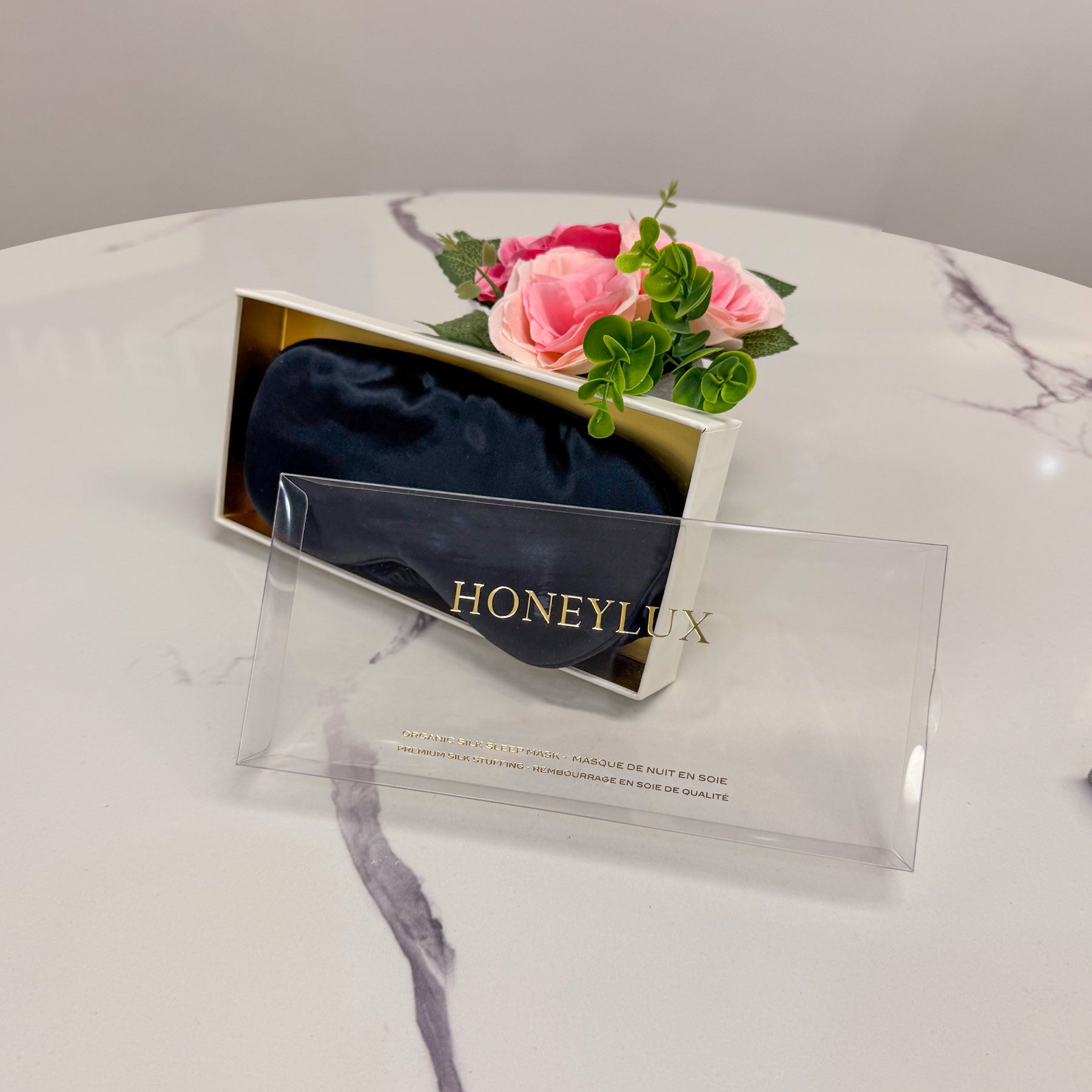 Honeylux black silk sleep mask in packaging with flowers, gift presentation.