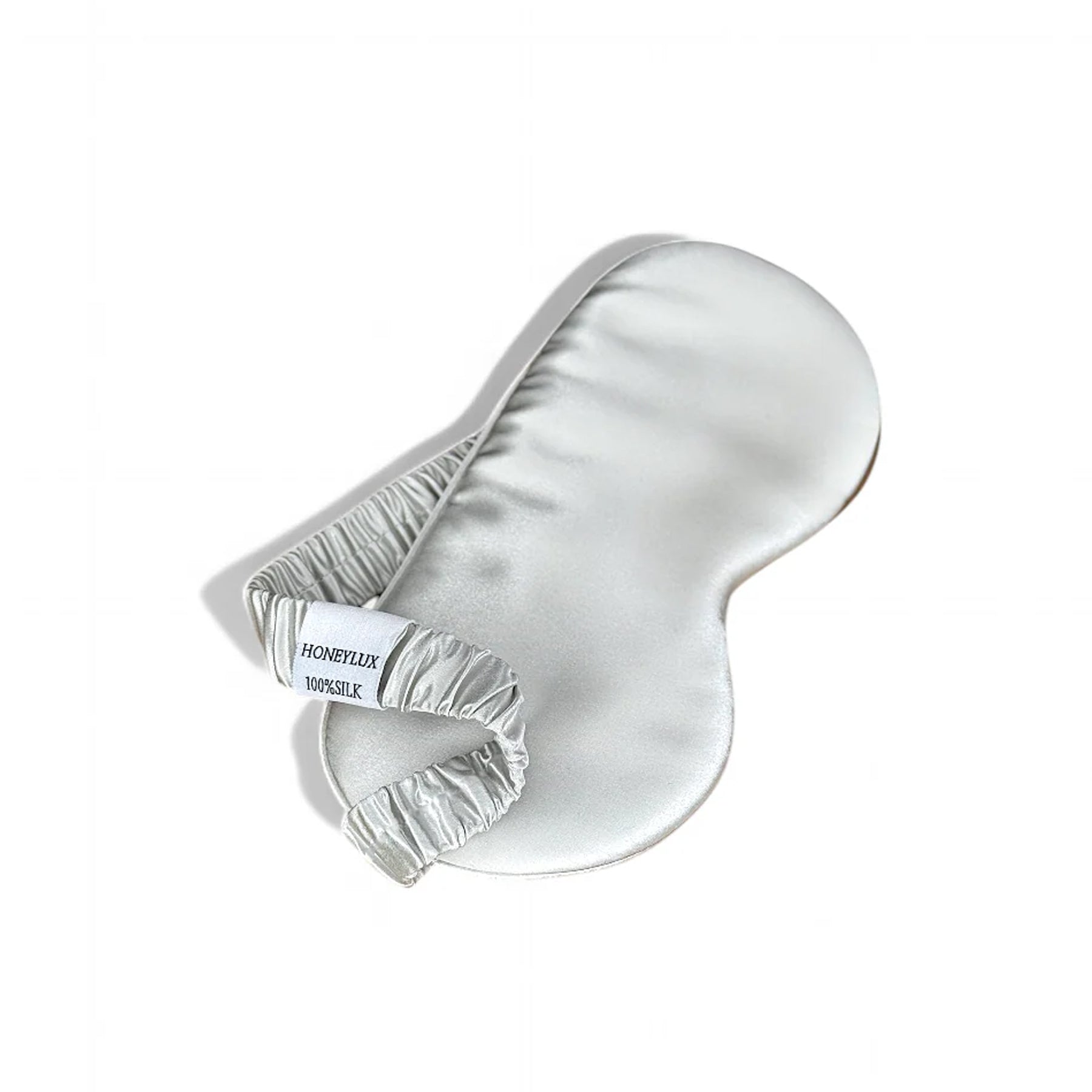 Light grey silk eye mask with ruched elastic band and Honeylux label, angled product shot.