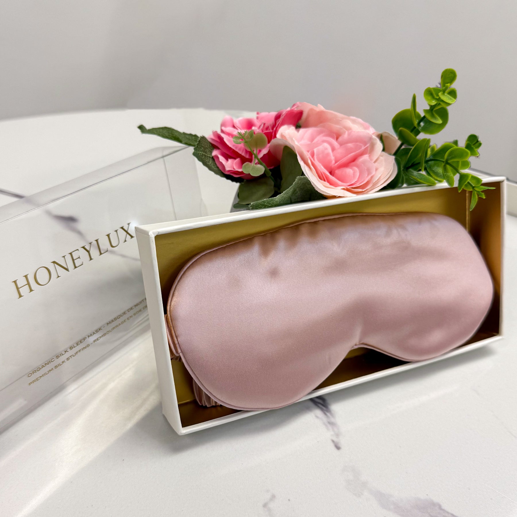 Honeylux pink silk sleep mask in gift box with pink flowers, luxury presentation.
