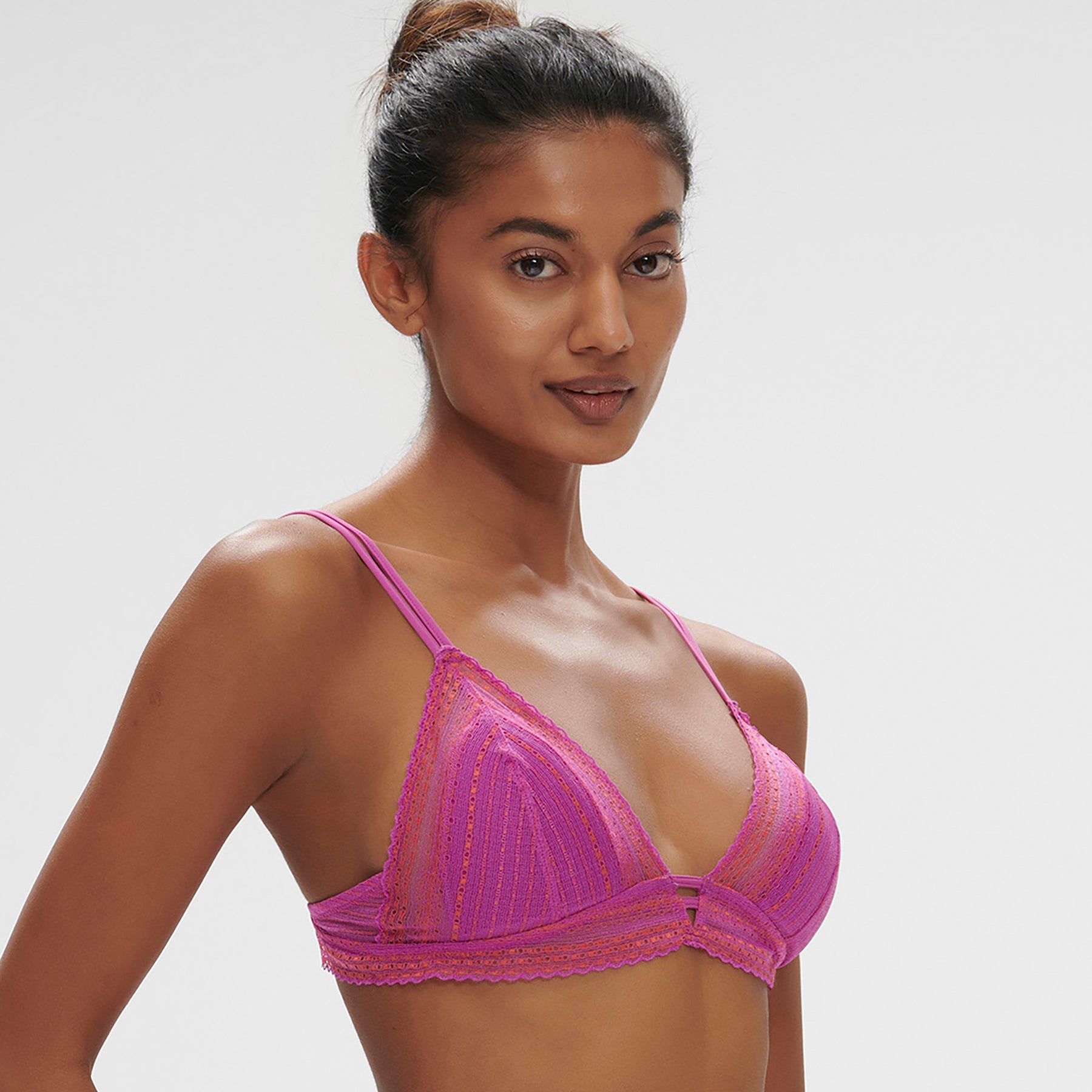 Sheer, lace wireless triangle bralette in energy pink/hot pink. Front view, closeup on model shown with matching thong.