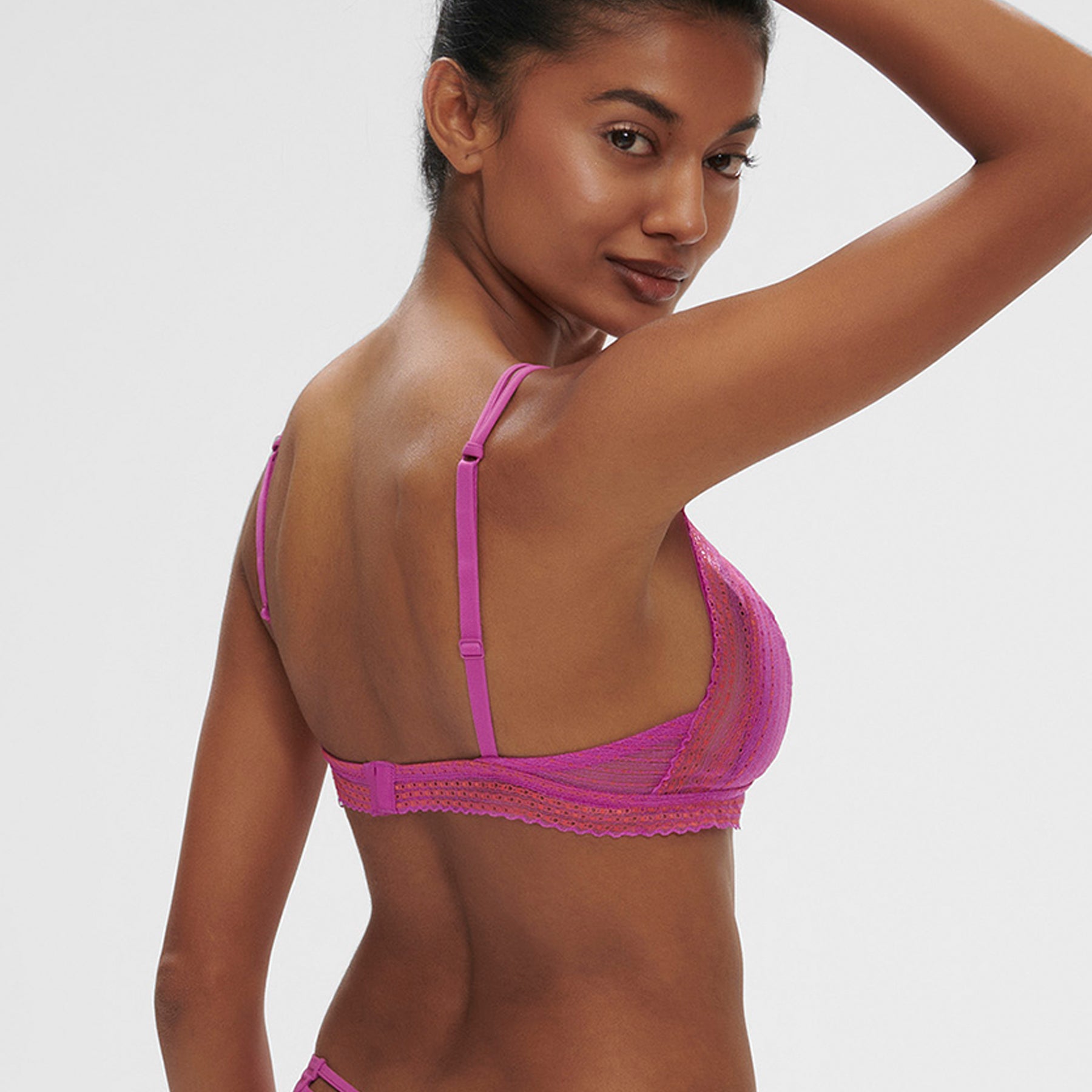 Sheer, lace wireless triangle bralette in energy pink/hot pink. Rear view, on model.