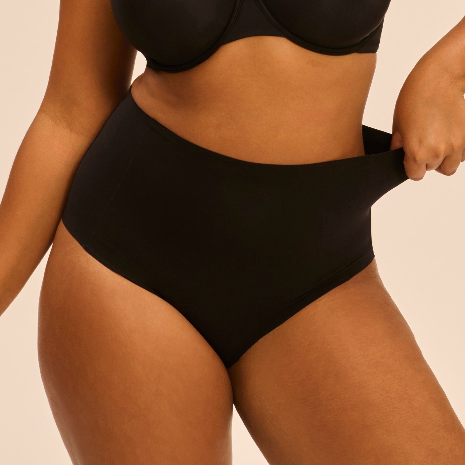 Simone Perele Story Control Full Brief in Black - curvy model adjusting waistband of high-rise control panty