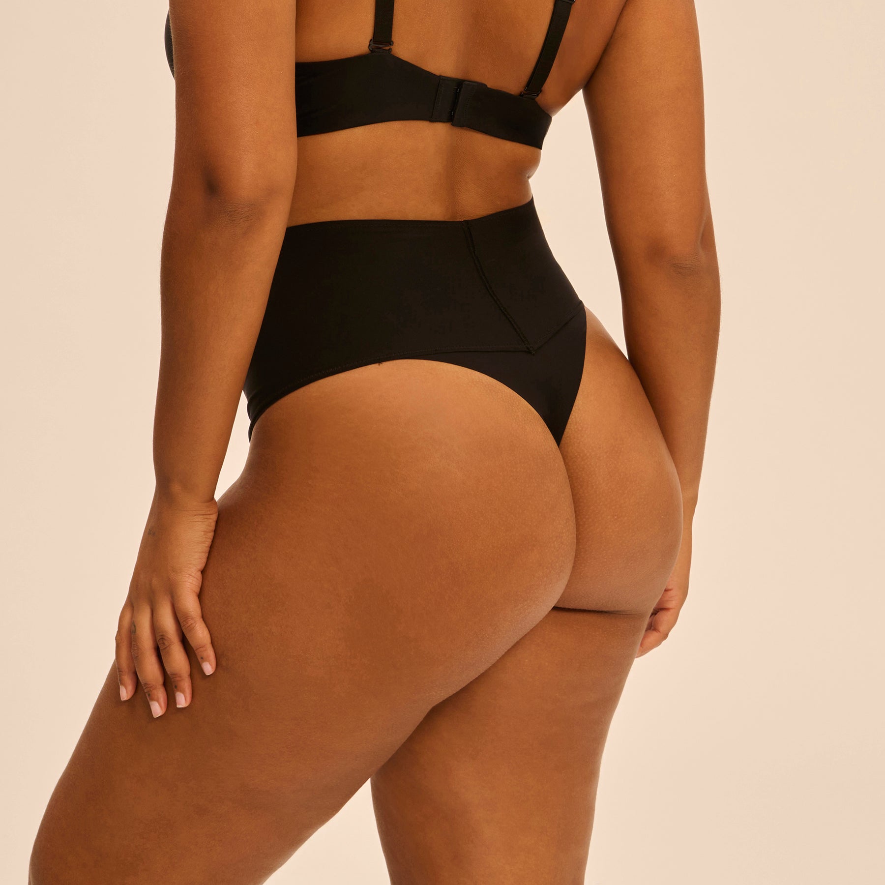 Side angle back view of Simone Pérèle black high-rise thong - smooth back coverage and sculpting fit ideal under fitted clothing.