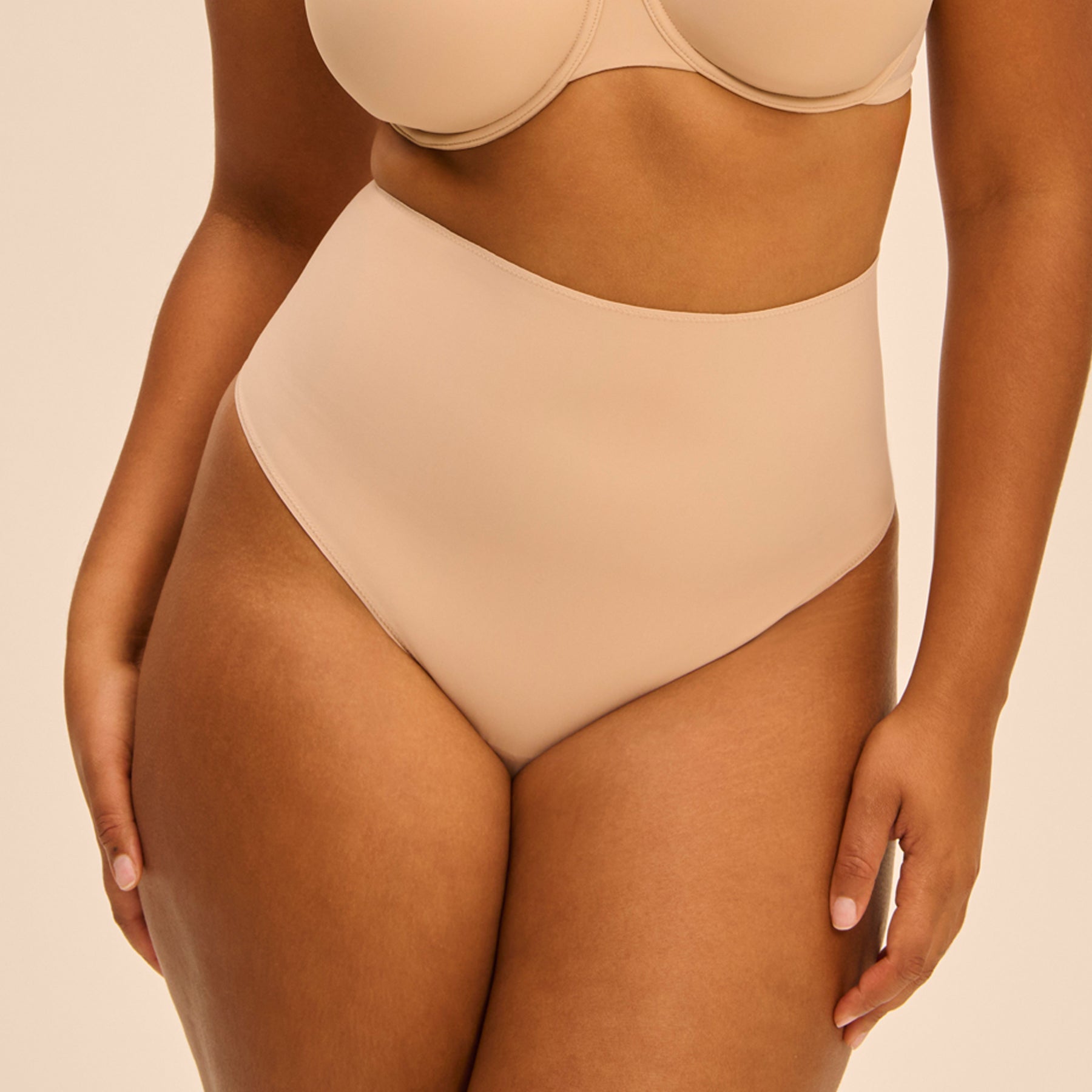 Plus-size model in Simone Pérèle high-waist thong in Peau Rosée - front shaping coverage.