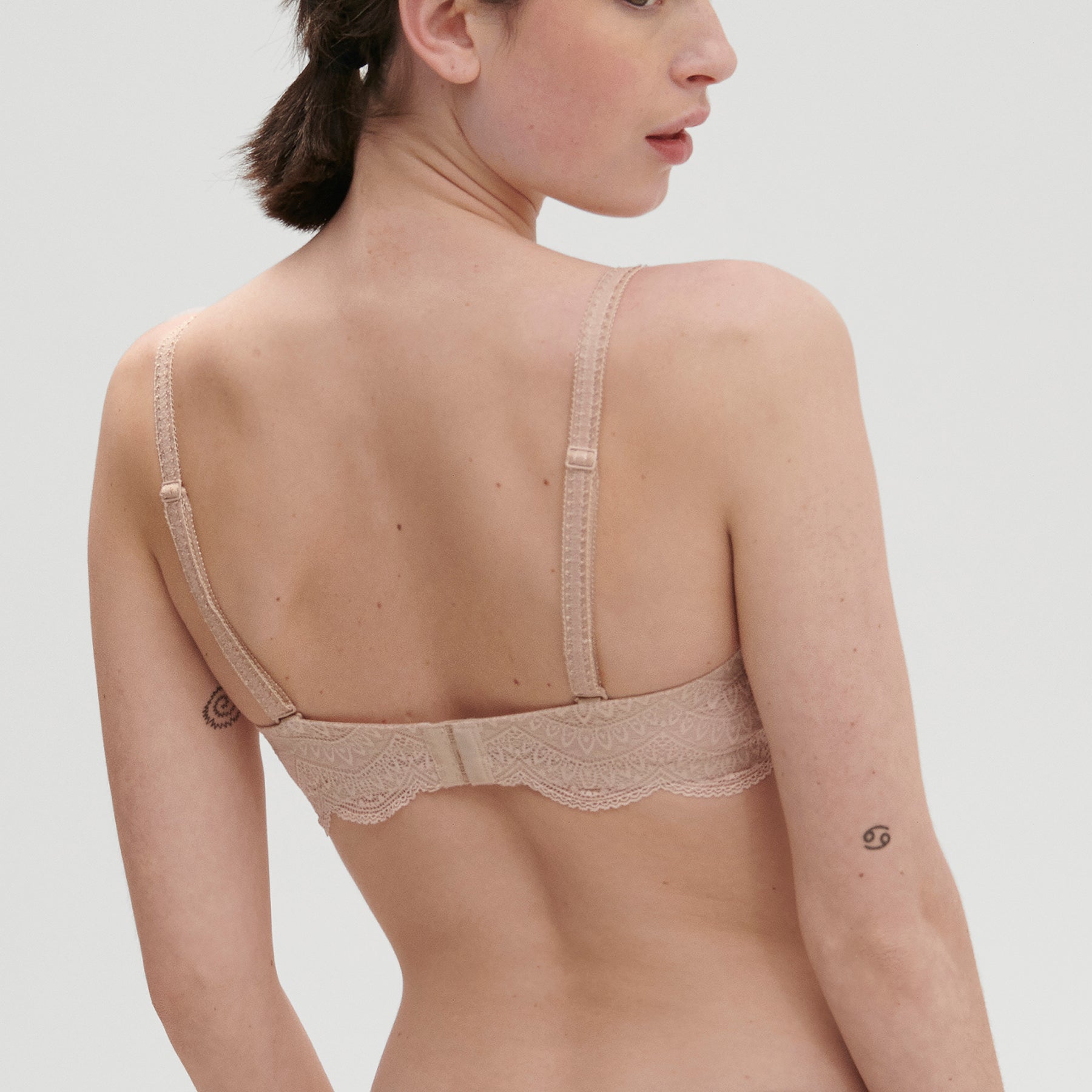 Strapless bra in nude peau rose, on model, rear view.