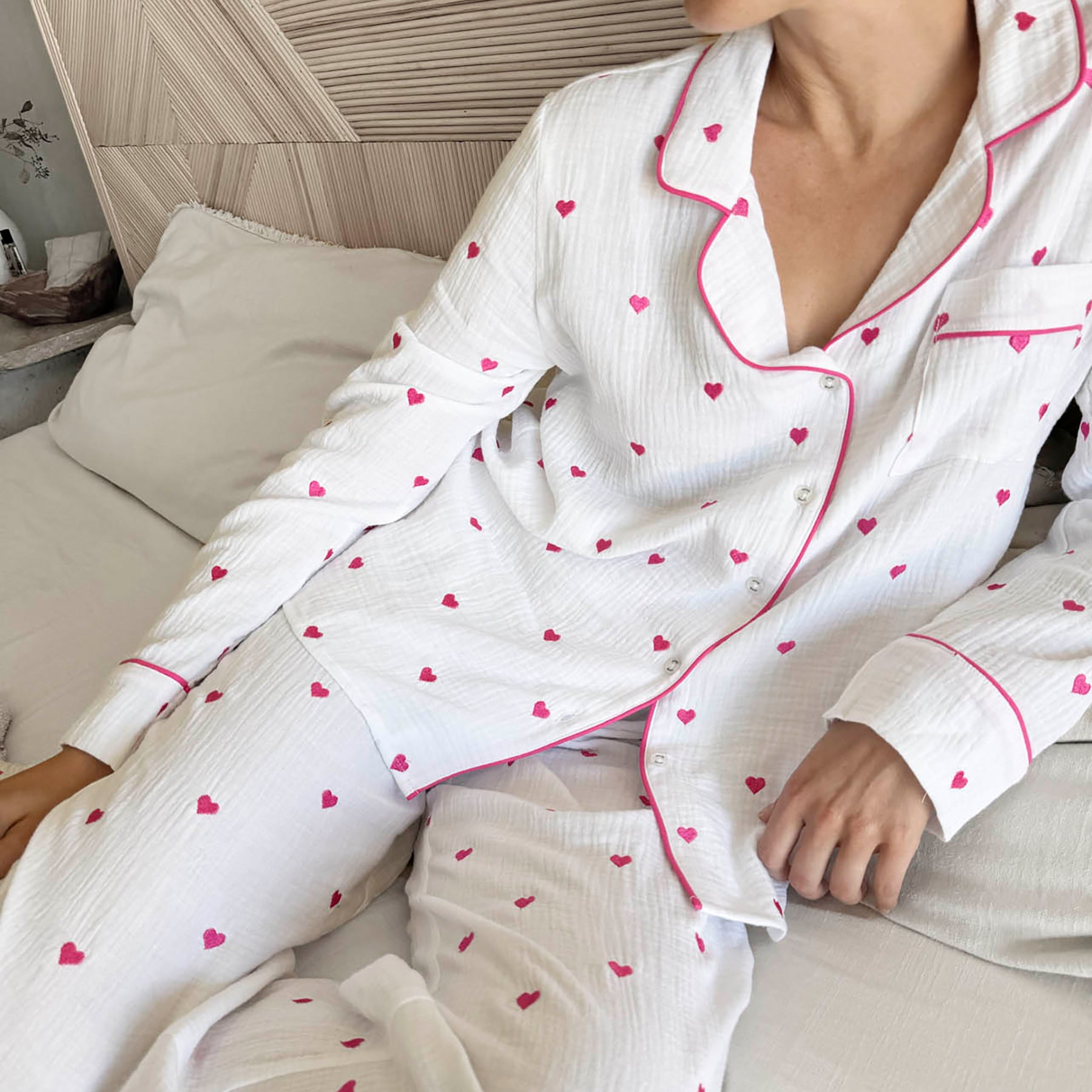 classic button up pyjama set in crinkle cotton in white with mini hot pink embroidered hearts. Matching hot pink contrast piping on trims. Front view close up 2 on model.