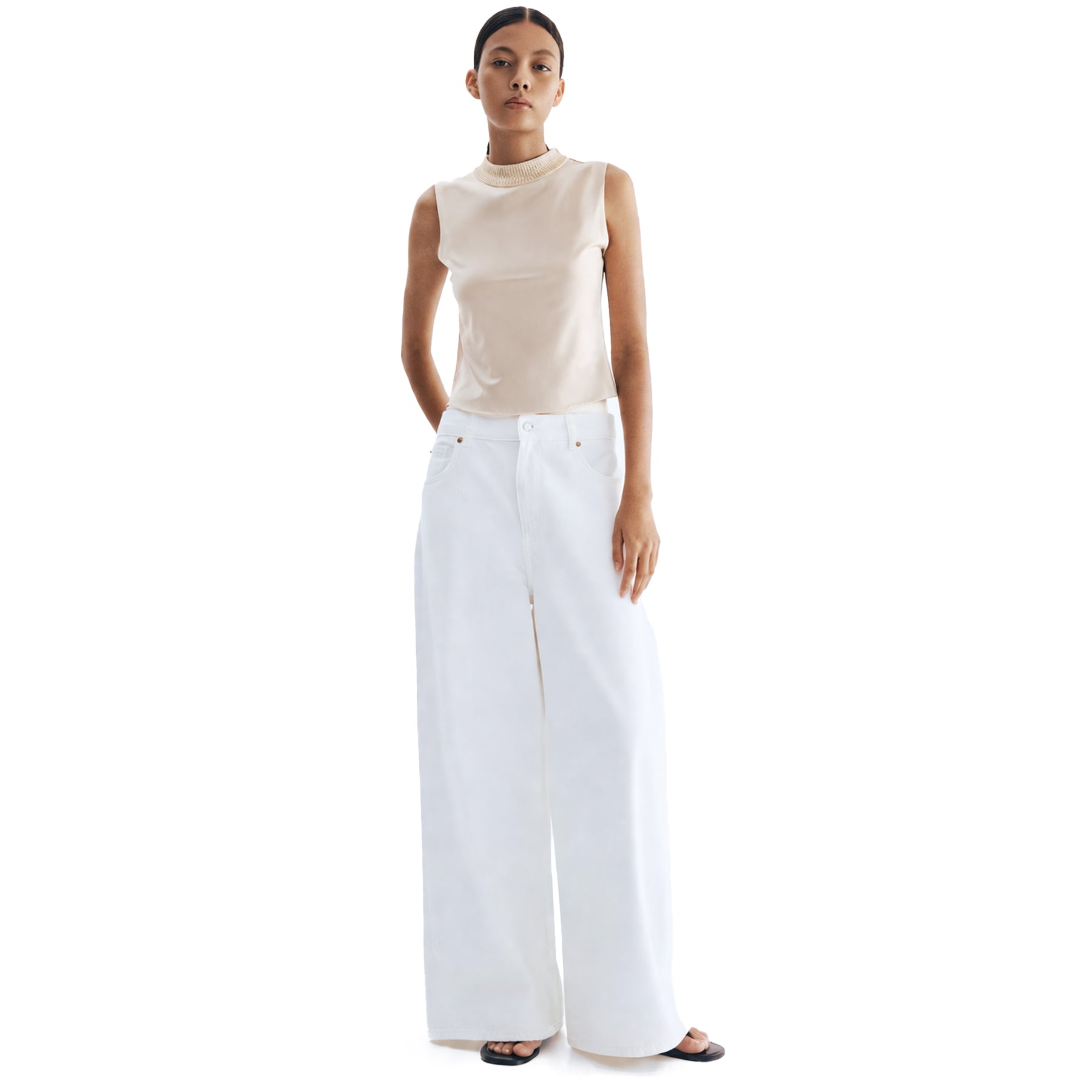 Model wearing off-white sleeveless satin blouse with textured neckline, styled with wide-leg white pants for a clean, modern look.