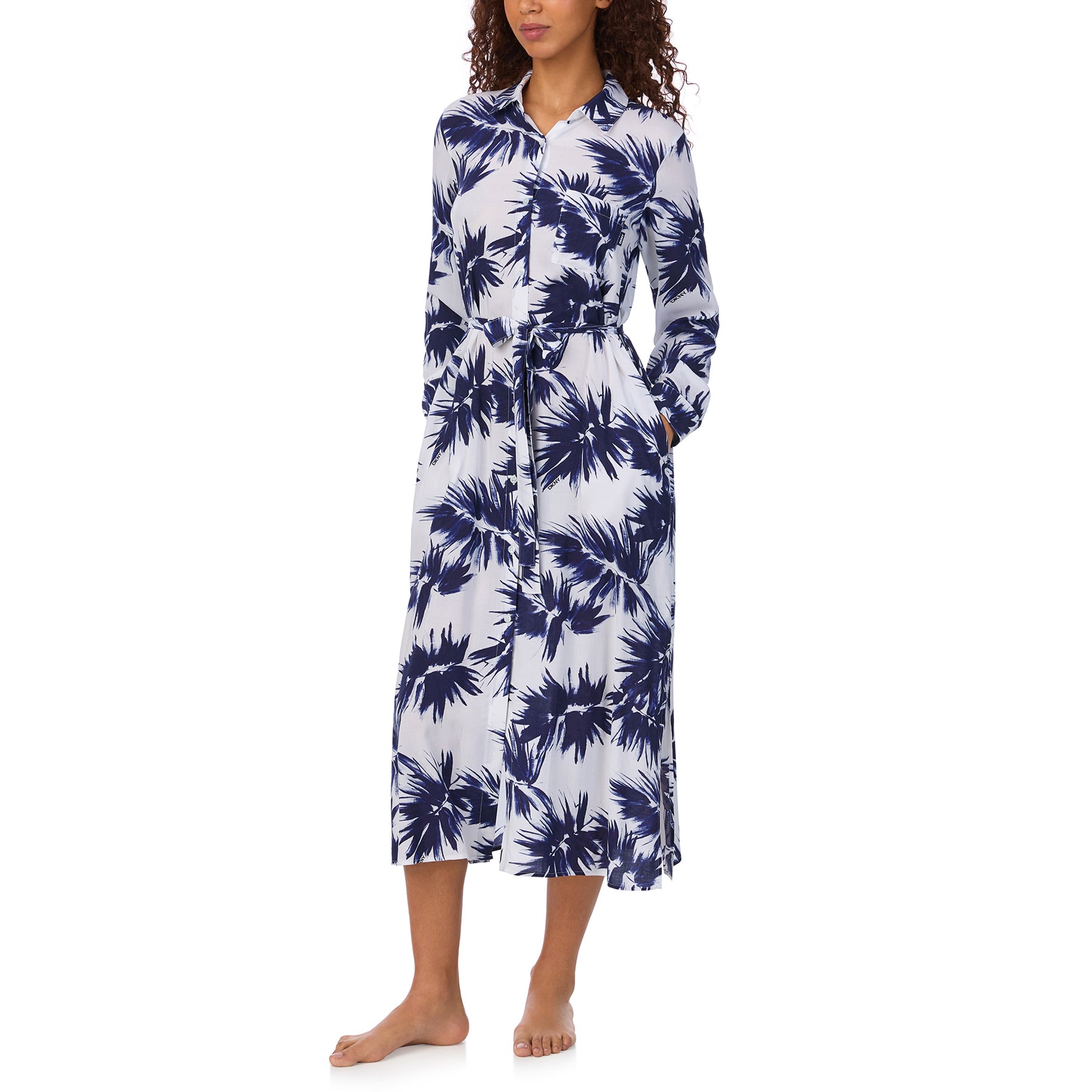 Model wearing a navy palm-print shirt dress with long sleeves, belted waist, and side pockets.