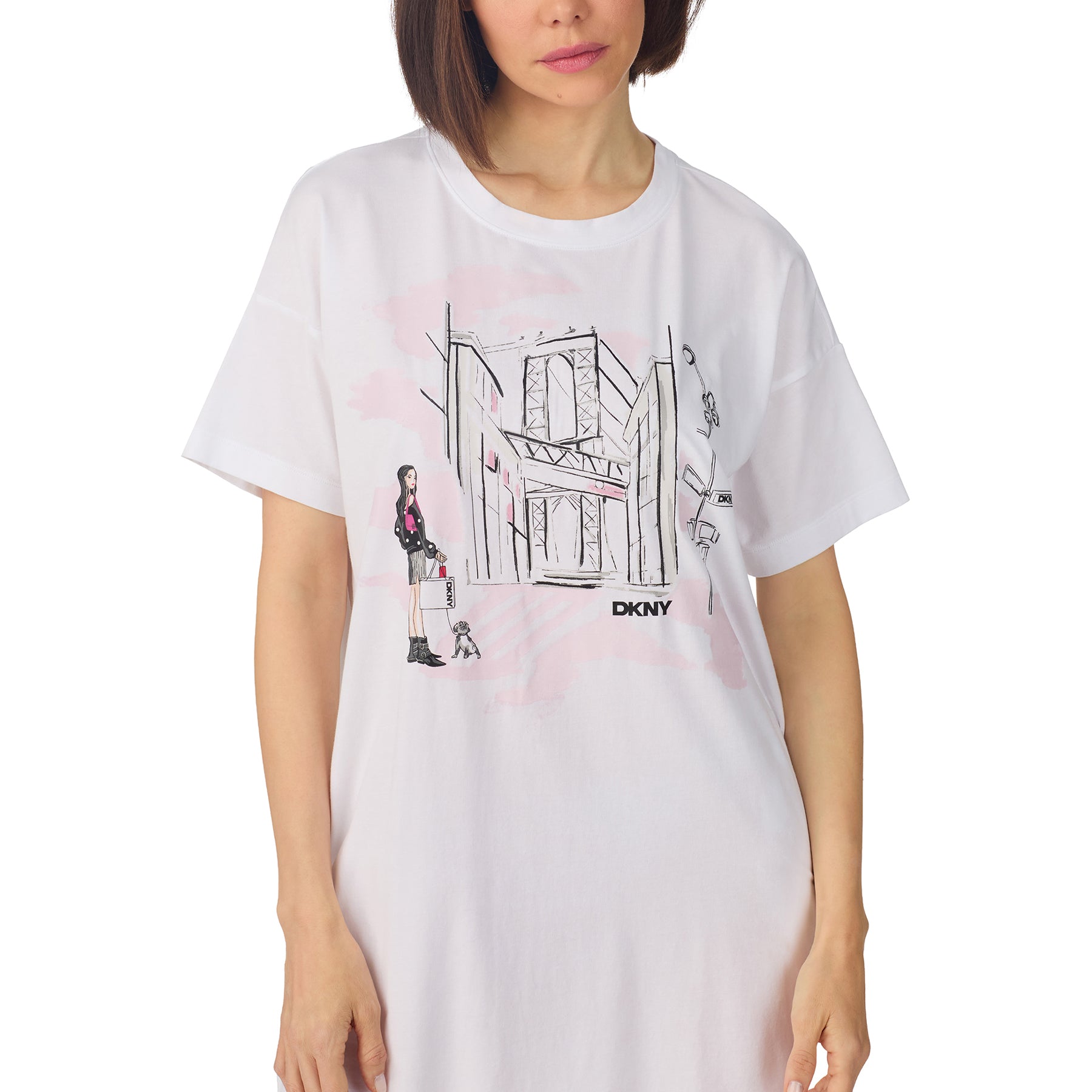Woman wearing white DKNY sleep shirt dress with pink city illustration and short sleeves.