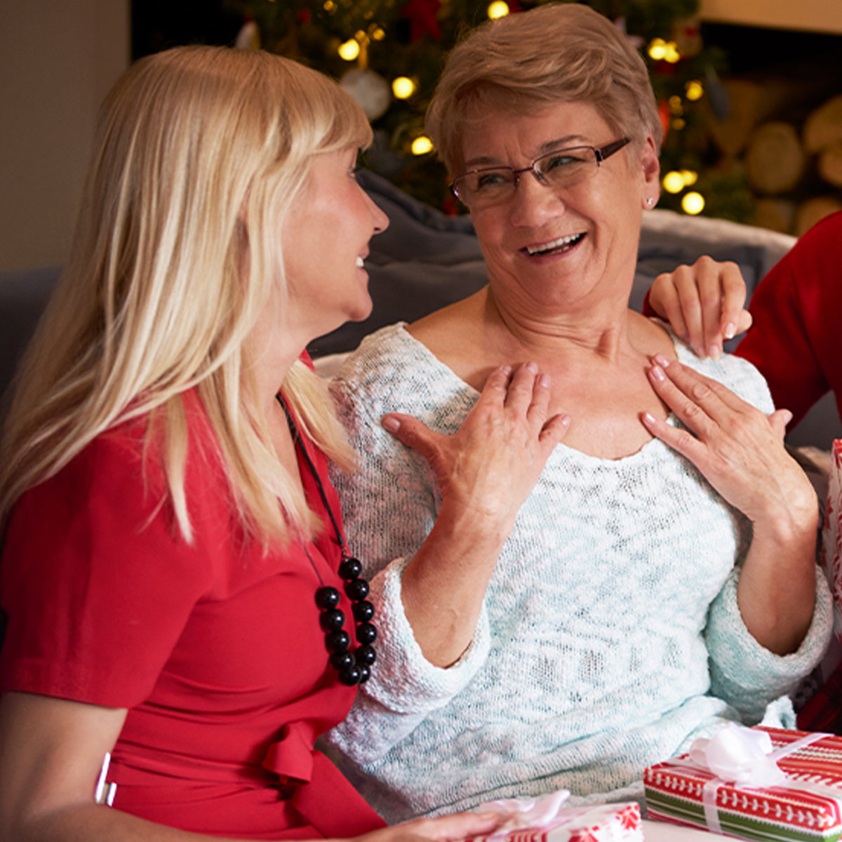 A women hugging her mom, giving her a Christmas present.