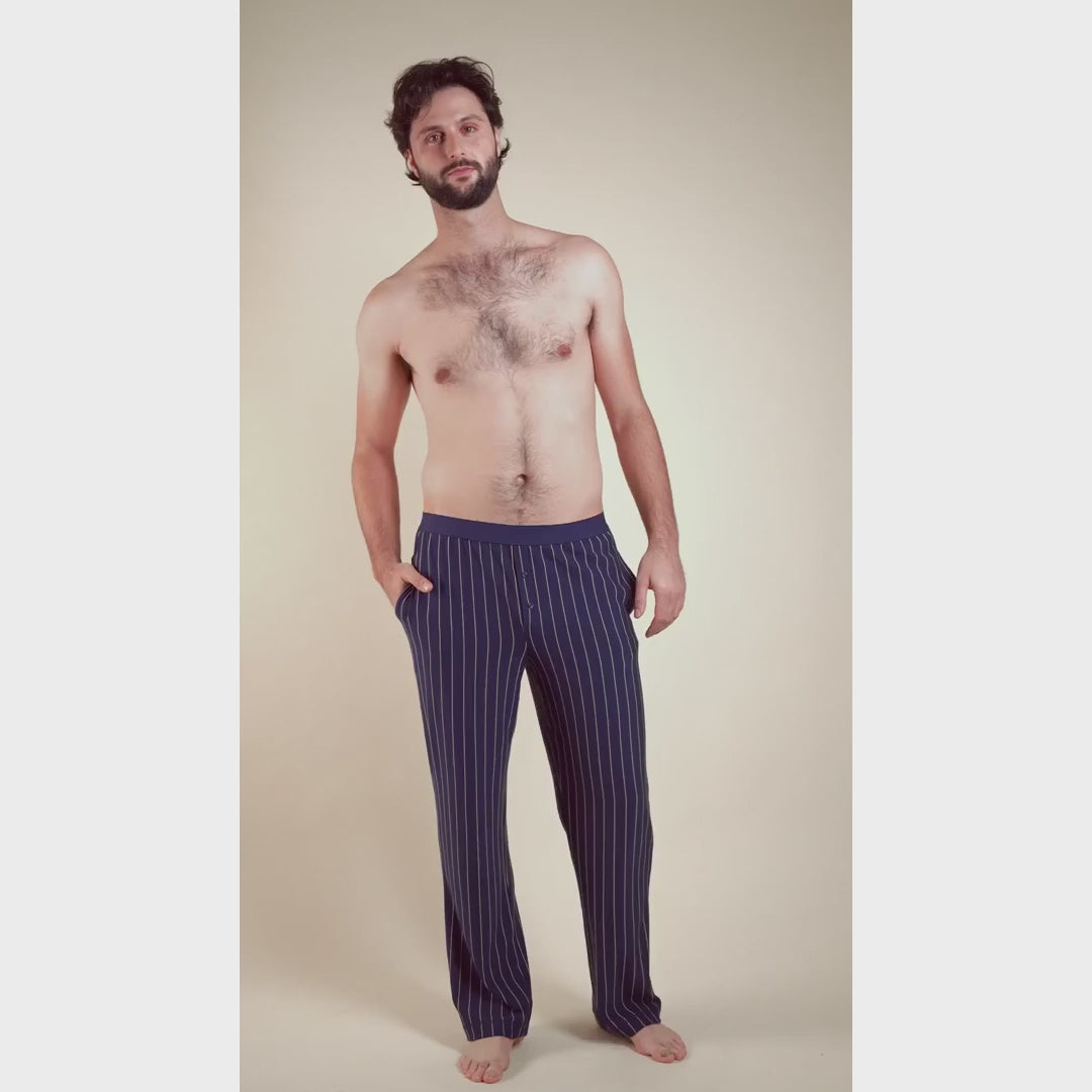 Model wearing men’s striped Fleur’t PJ pants in navy with button fly and soft breathable fabric, designed for comfort.